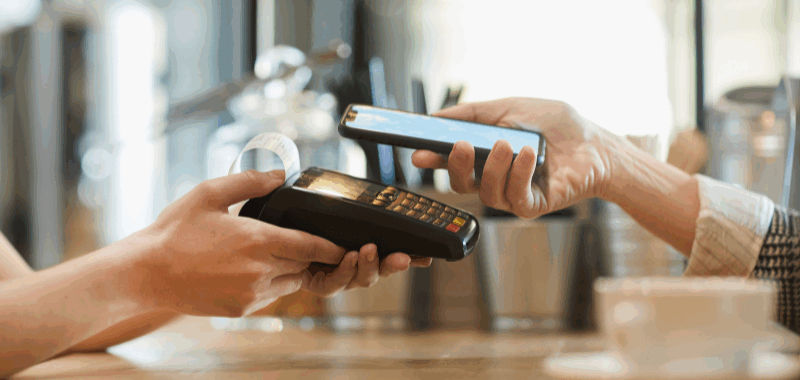 Persona realizando un pago sin contacto desde un smartphone en un café, simbolizando pagos digitales rápidos y seguros con tecnología SPEI.