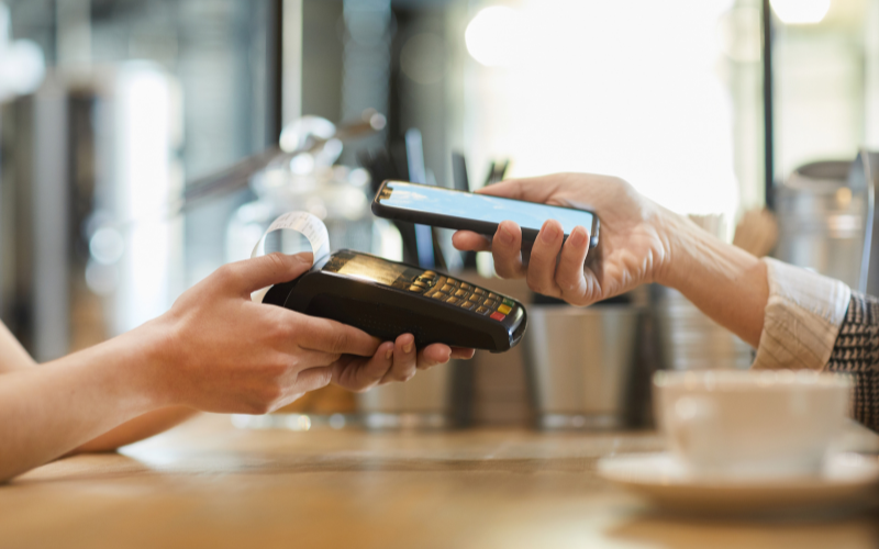 Persona realizando un pago sin contacto desde un smartphone en un café, simbolizando pagos digitales rápidos y seguros con tecnología SPEI.