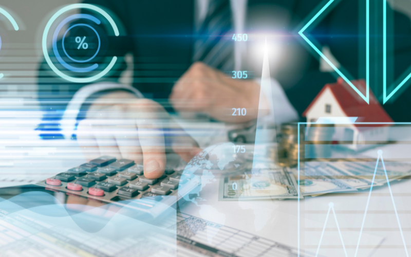 Ejecutivo financiero usando calculadora con gráficos, billetes y casa en miniatura, representando el uso de tecnología para gestionar riesgos operacionales.