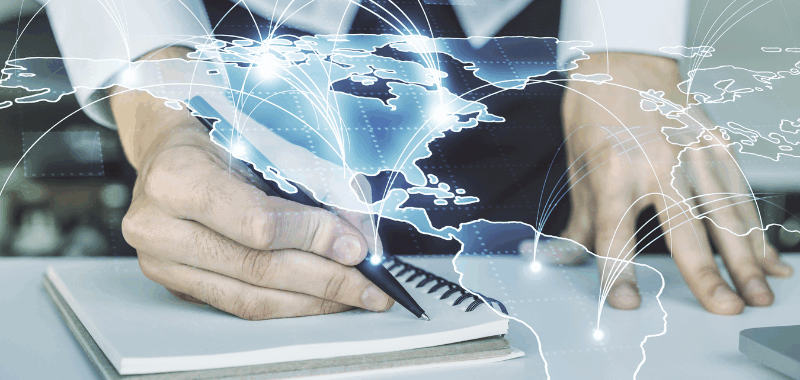 Manos escribiendo en un cuaderno mientras un mapa digital global muestra conexiones entre países, representando la armonización normativa internacional y la transformación regulatoria y tecnológica del sector financiero en México